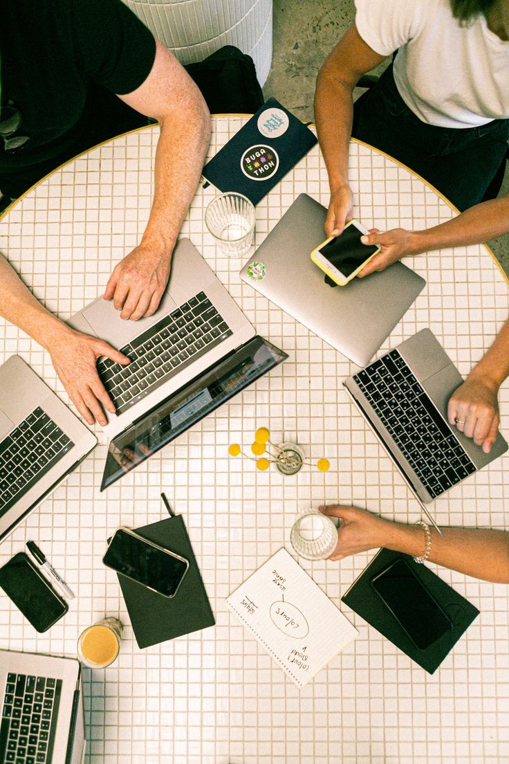 Équipe au travail autour d'une table avec ordinateurs et téléphones